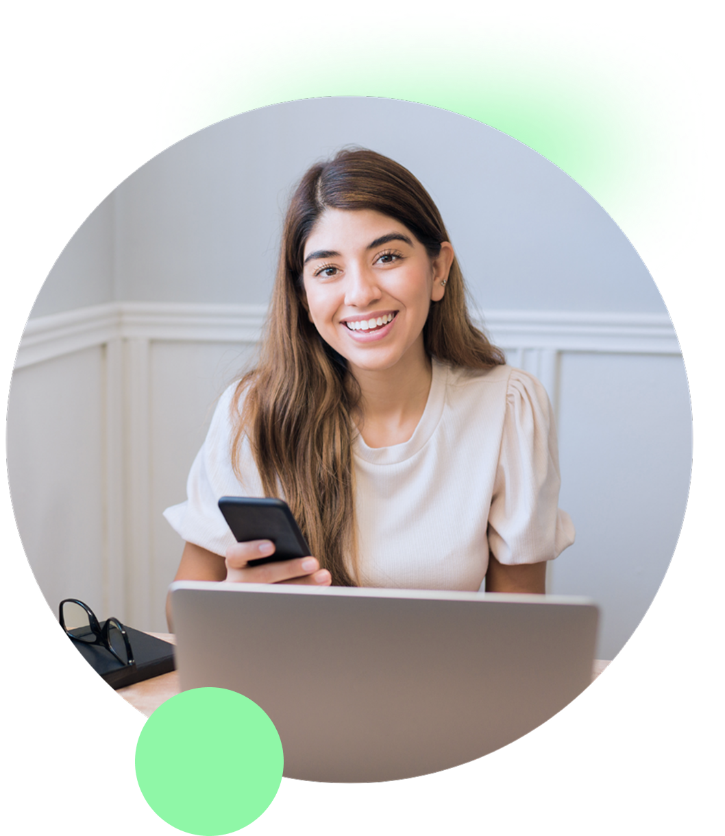 girl smiling to the front using a phone and a laptop